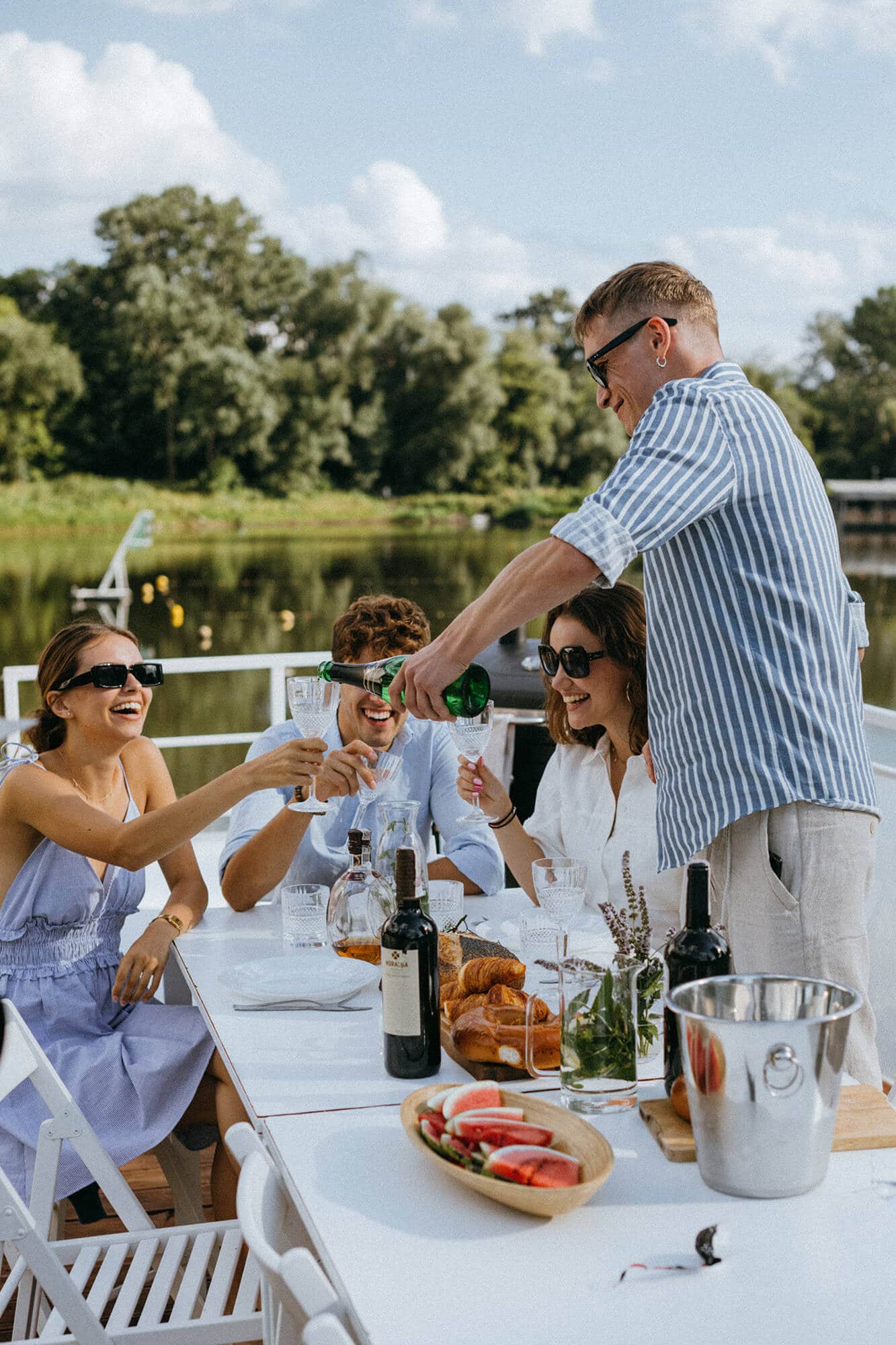 Four celebratory people drinking wine on a dock depicting the vibrant lifestyle at Flora apartments in summerville sc - pexels koolshooters 9750952