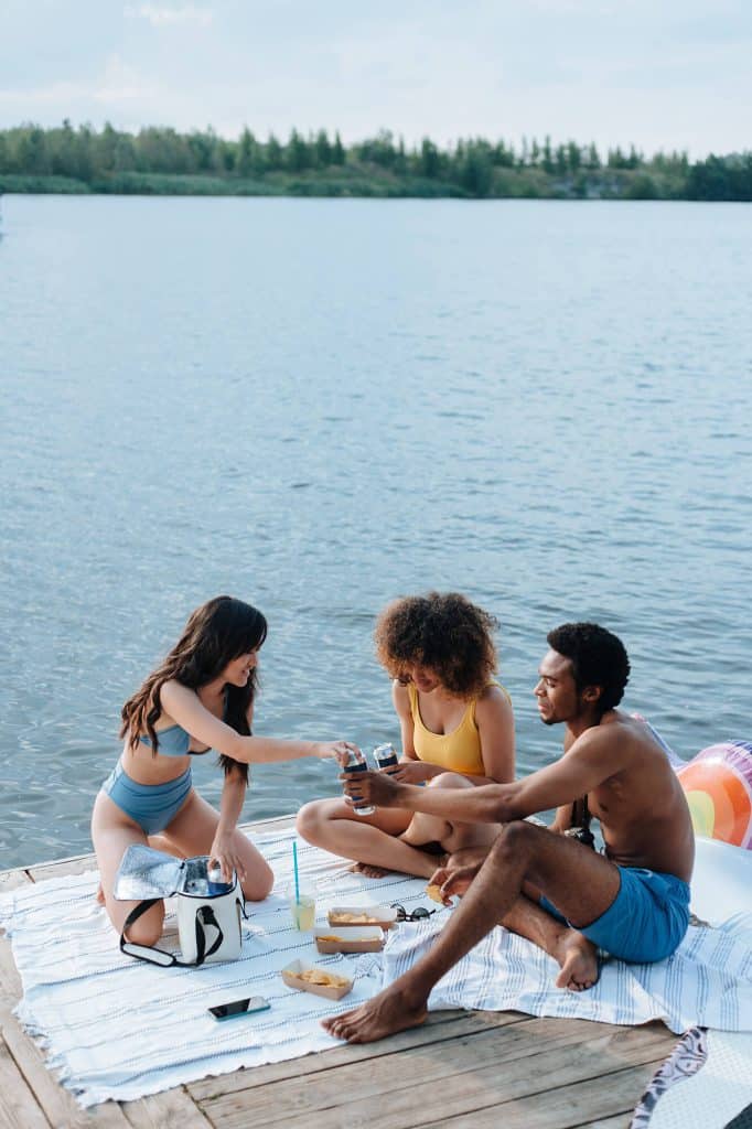 Three people enjoying snacks on a dock depicting the vibrant lifestyle at Flora apartments in summerville sc - pexels ron lach 9974363